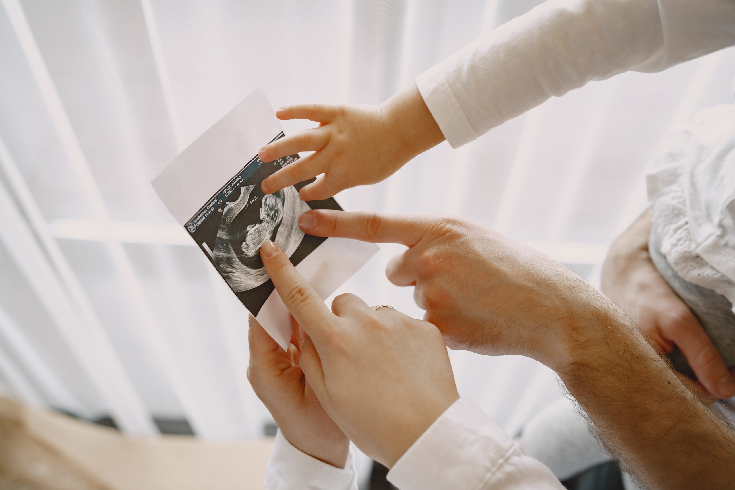 mom, dad and doctor pointing to fetus ultrasound