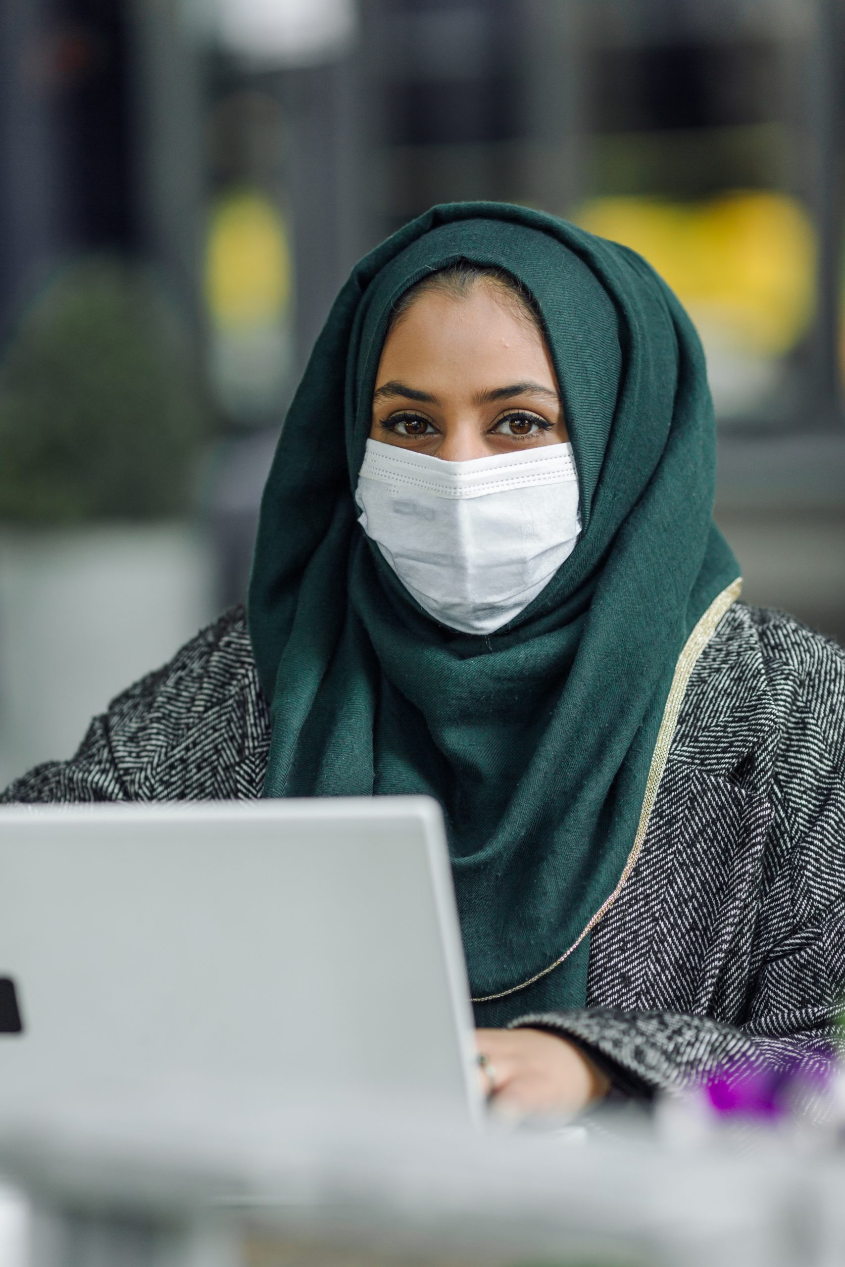 emirati woman working on laptop smiling at camera