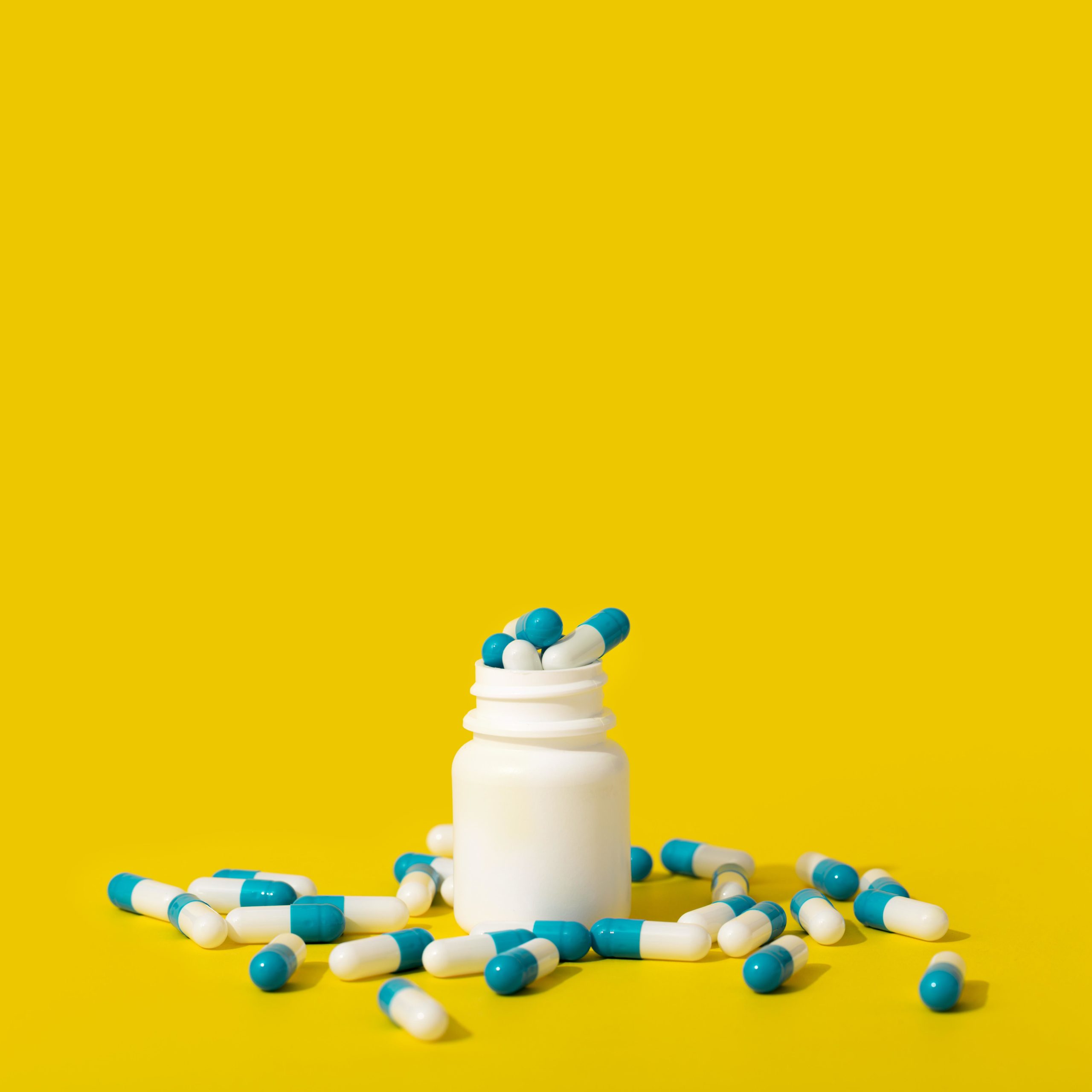 container of overflowing medicine with yellow background